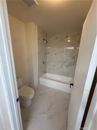 a bathroom with a granite countertop toilet and a shower