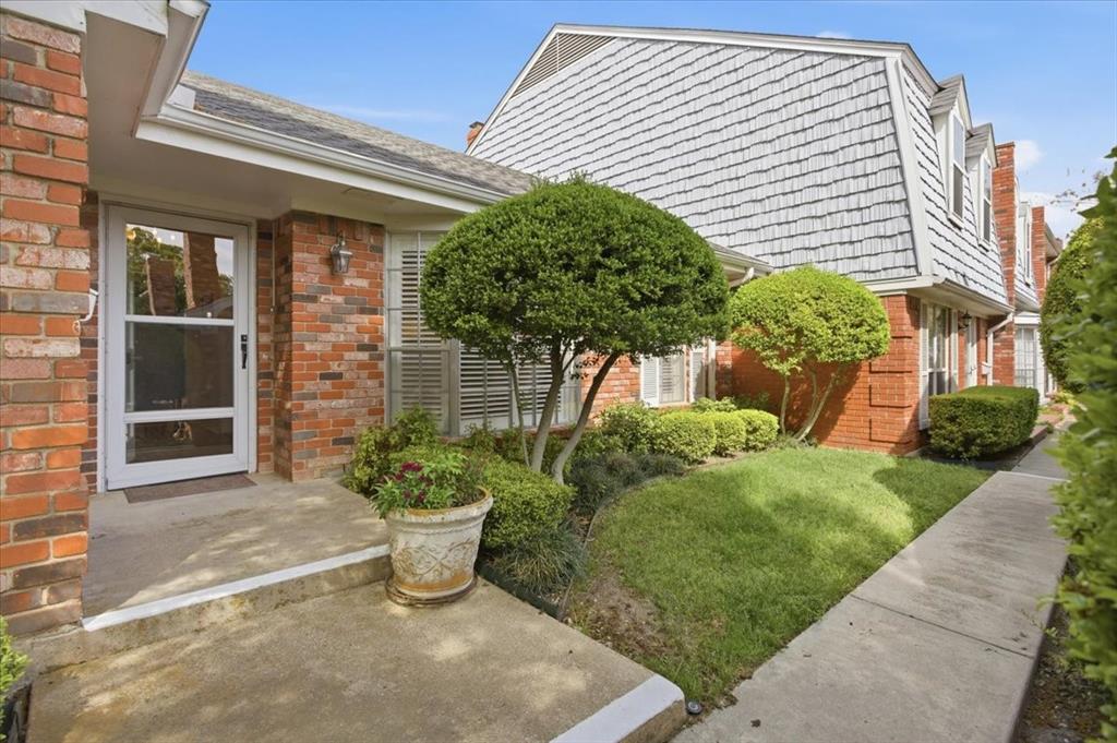 Property entrance with brick siding and a lawn