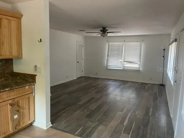 an empty room with wooden floor cabinet and windows