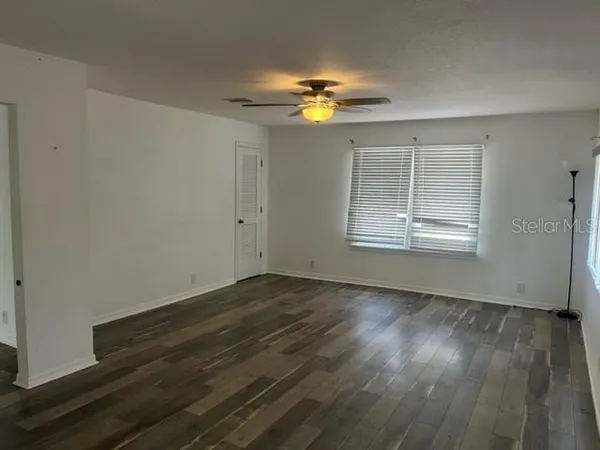 a view of an empty room with wooden floor and a window