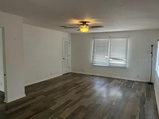 a view of an empty room with wooden floor and a window