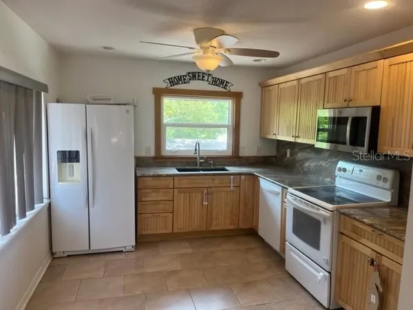 a kitchen with stainless steel appliances granite countertop a refrigerator a stove a sink and a microwave