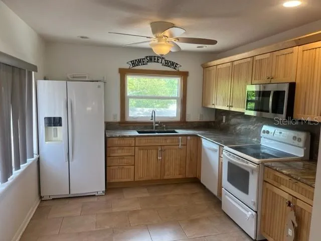 a kitchen with stainless steel appliances granite countertop a refrigerator a stove a sink and a microwave