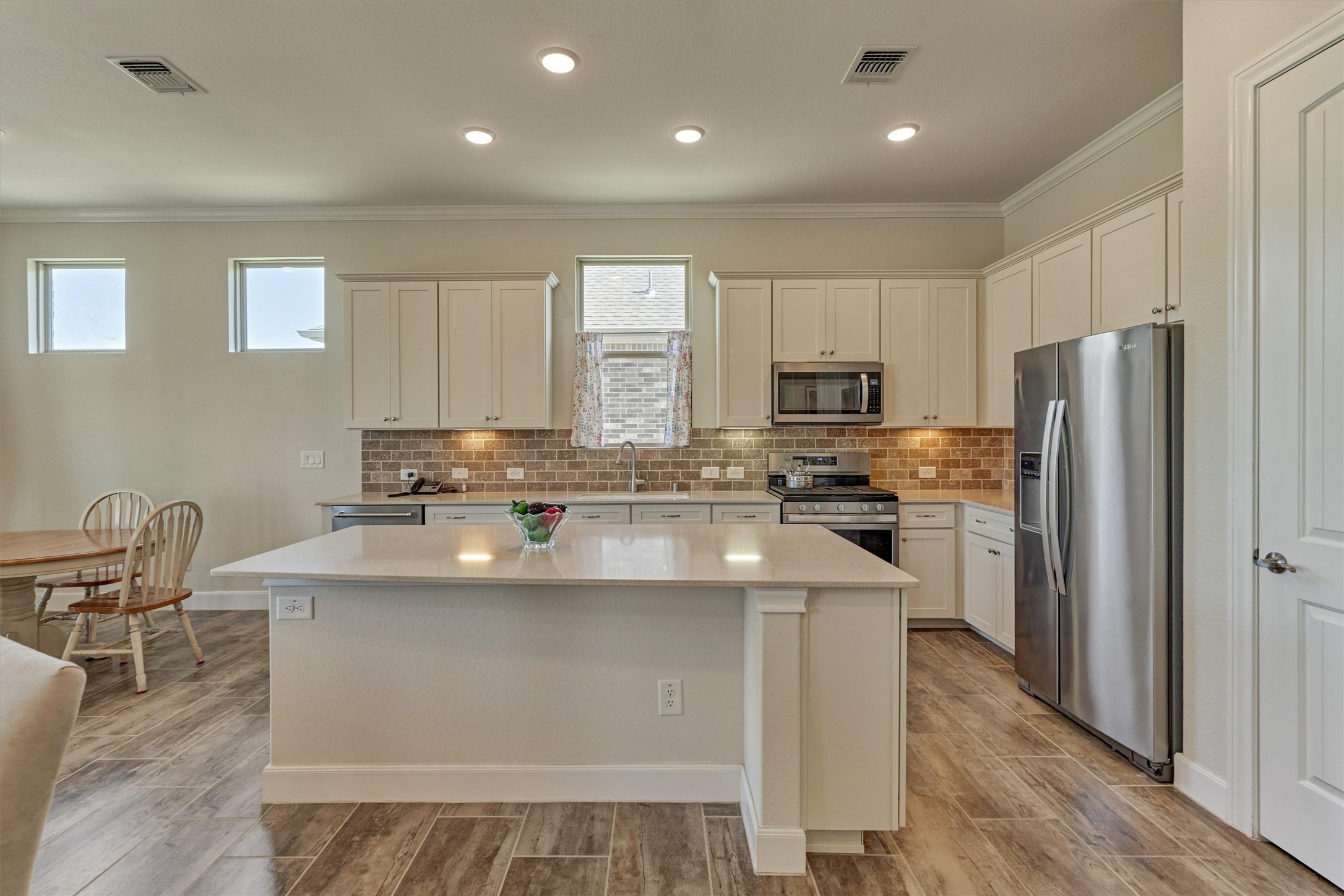 132 Chestnut Bay Spring, TX 77382 - Photo 19 of 33 a kitchen with kitchen island stainless steel appliances a sink a stove a refrigerator cabinets and a dining table