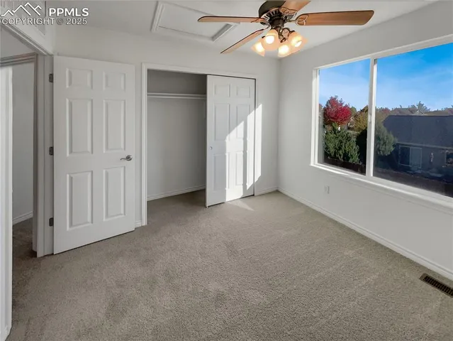 an empty room with windows and ceiling fan