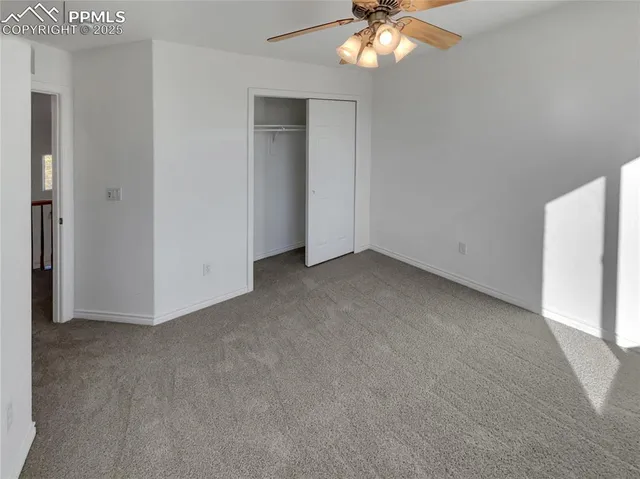 an empty room with a chandelier fan and windows