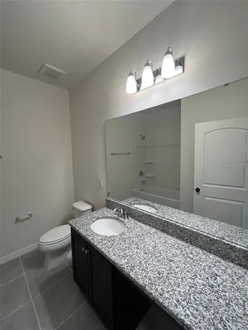 a bathroom with a granite countertop sink a toilet and a mirror