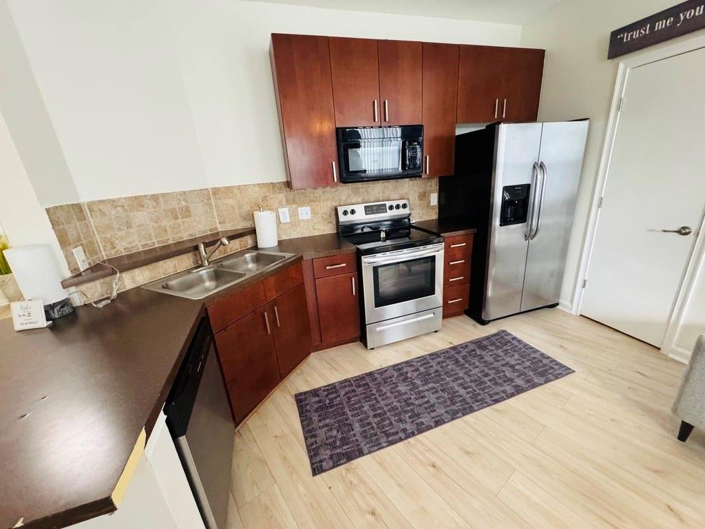 898 Oak Street Southwest, Unit 1214 Atlanta, GA 30310 - Photo 5 of 23 a kitchen with stainless steel appliances a stove a refrigerator and wooden cabinets