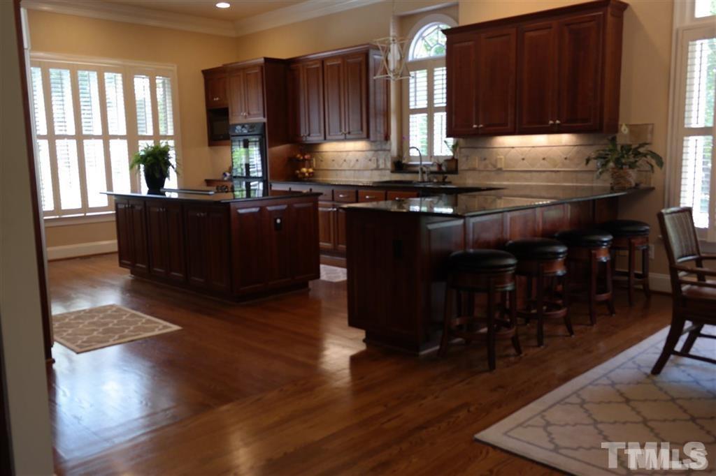 12928 Victory Church Road Raleigh, NC 27613 - Photo 14 of 25 a kitchen with granite countertop a stove a sink and wooden cabinets