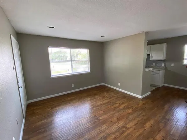 an empty room with wooden floor cabinet and windows