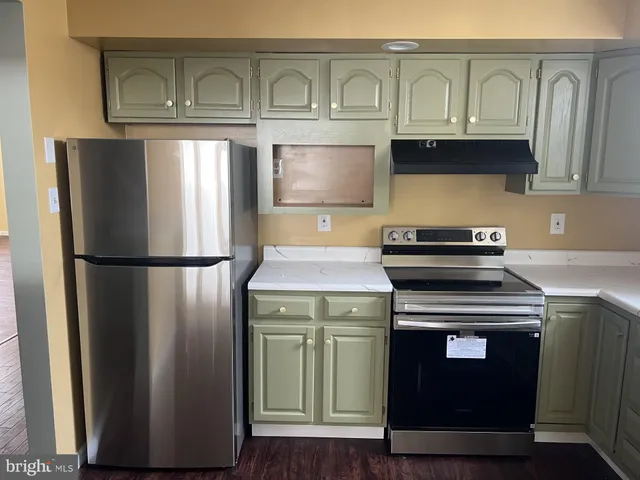 a kitchen with stainless steel appliances granite countertop a refrigerator a stove and a sink with wooden floors