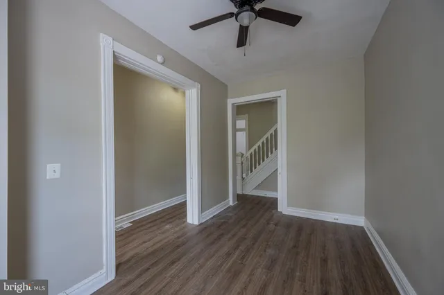 a view of hallway with wooden floor and a ceiling fan