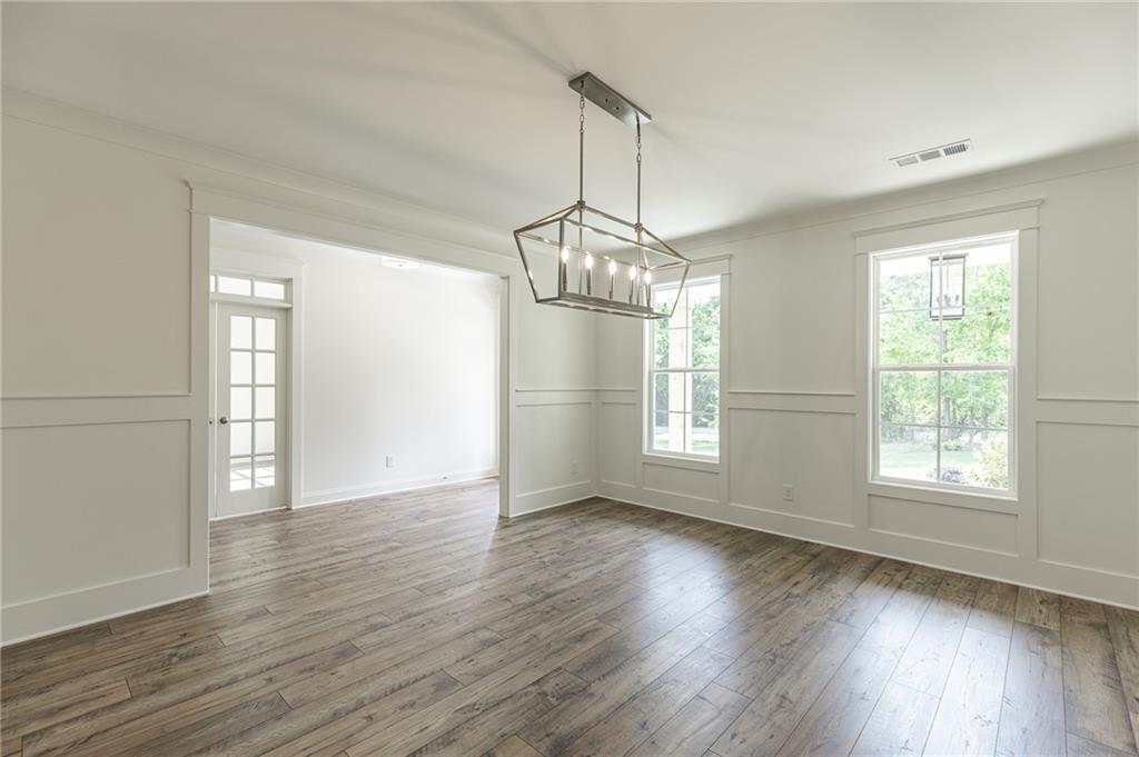 1210 Austin Road Winder, GA 30680 - Photo 12 of 56 an empty room with wooden floor chandelier and windows