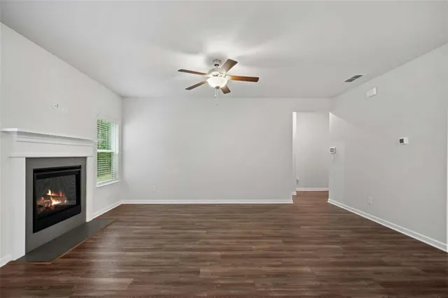 a view of an empty room with wooden floor fireplace and a window
