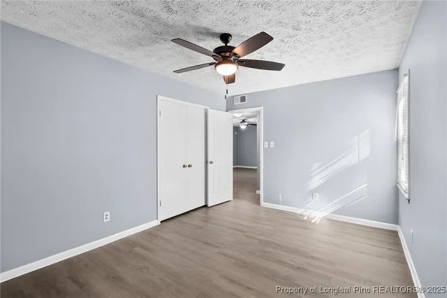 an empty room with wooden floor and ceiling fan