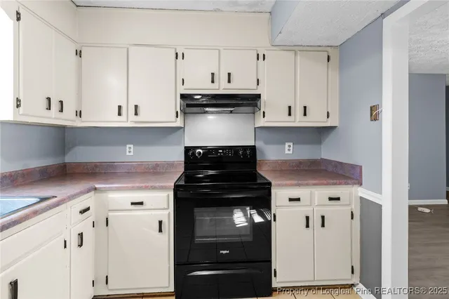 a kitchen with stainless steel appliances granite countertop a stove and a white cabinets