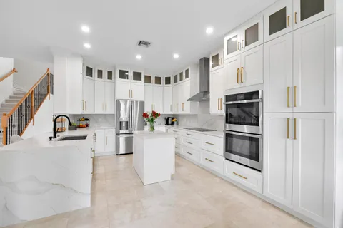a kitchen with stainless steel appliances kitchen island granite countertop a refrigerator and a stove top oven
