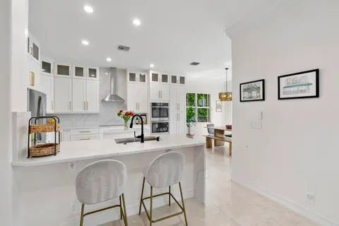 a large white kitchen with stainless steel appliances granite countertop a stove and a sink