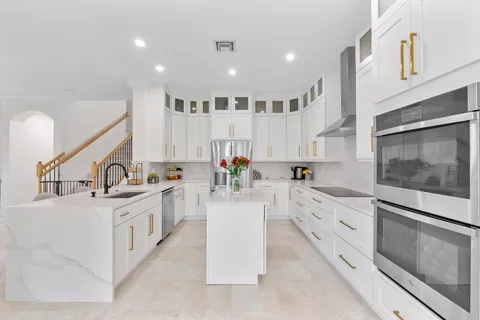 a kitchen that has a lot of white cabinets and a refrigerator