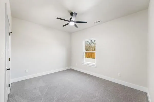 an empty room with a window and a ceiling fan