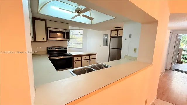 a large kitchen with stainless steel appliances a stove a refrigerator white cabinets and wooden floor