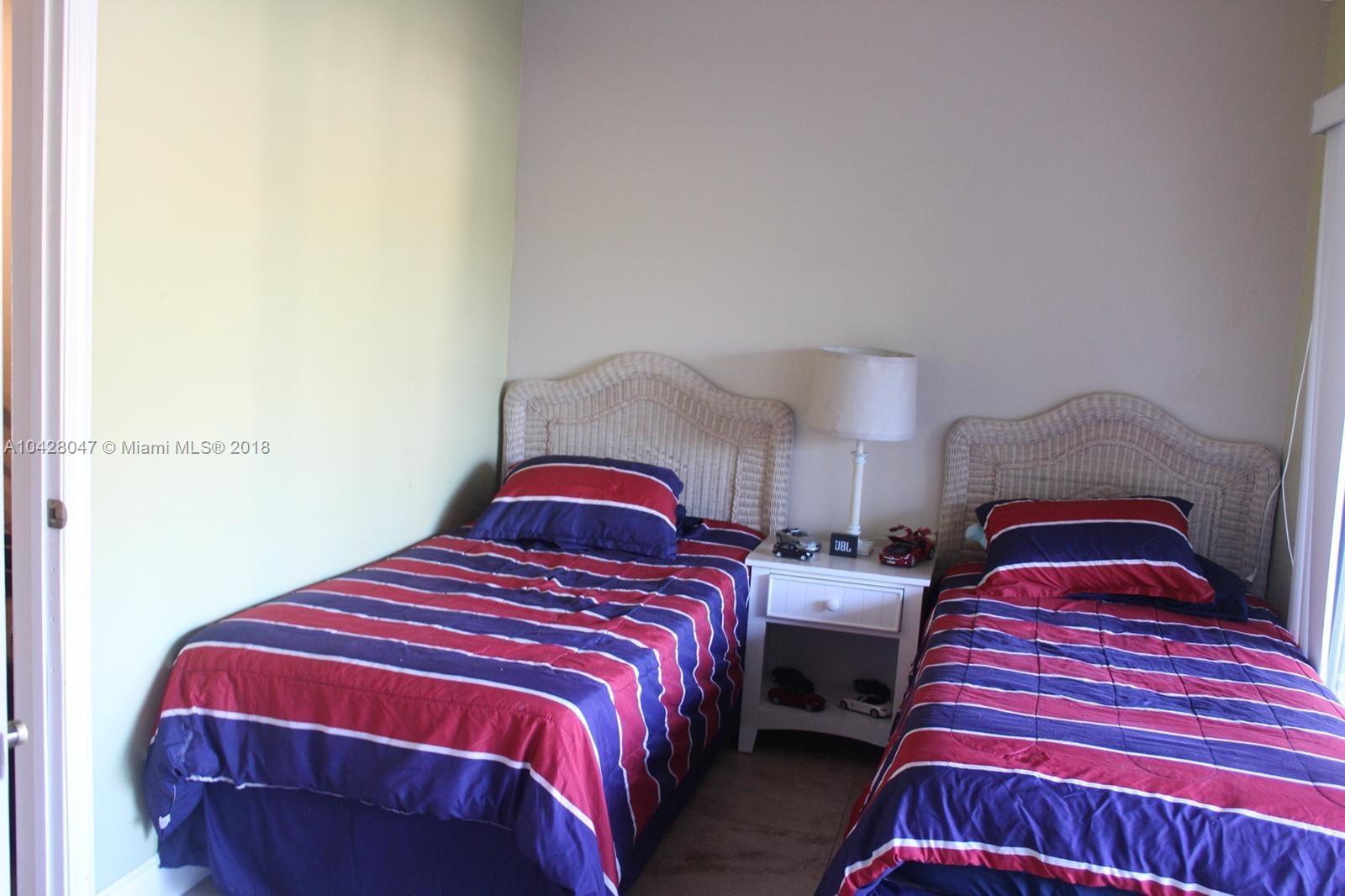 9511 Southwest 138th Place, Unit 9511 Miami, FL 33186 - Photo 11 of 17 a bedroom with two bed and a lamp