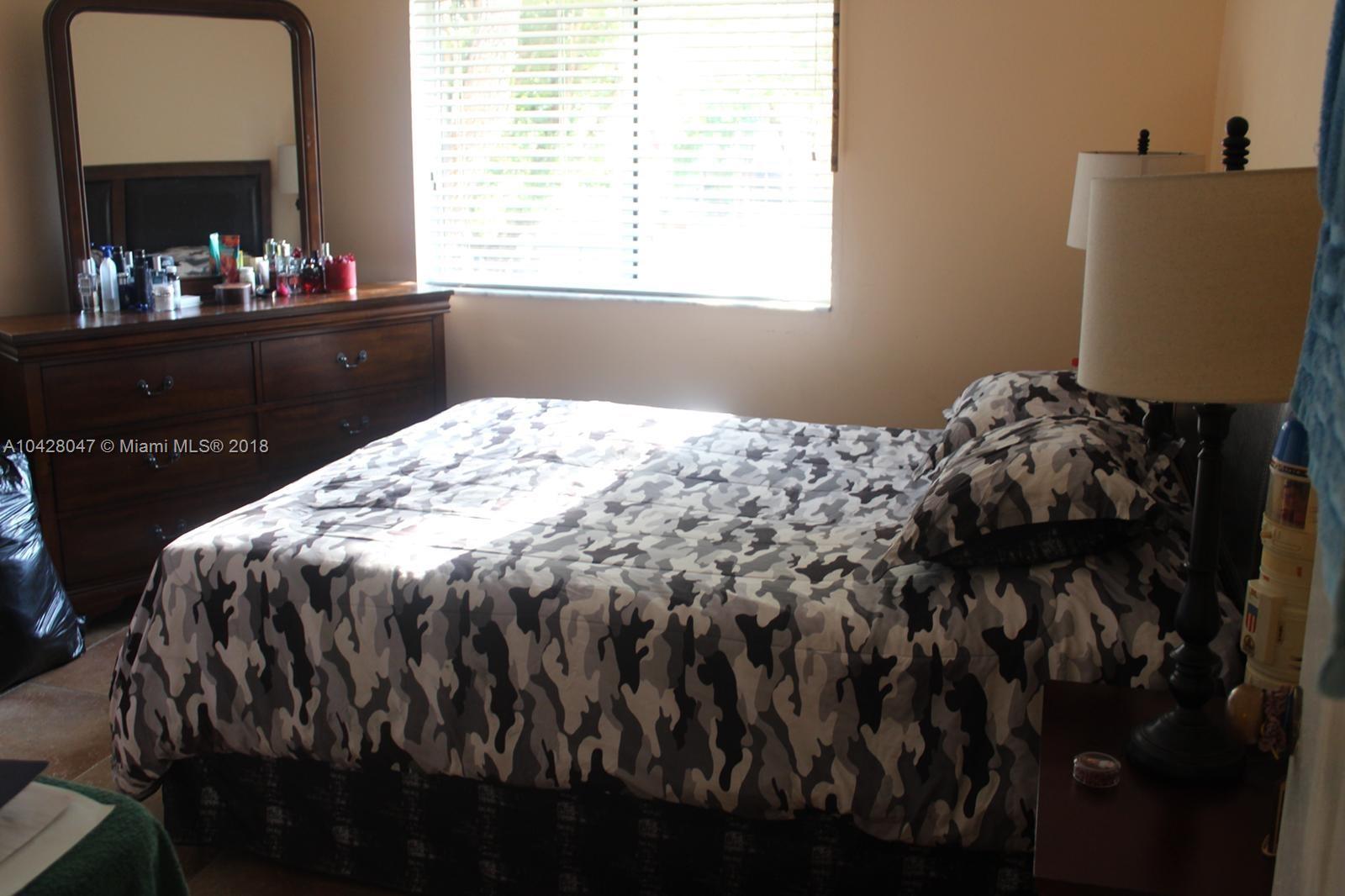 9511 Southwest 138th Place, Unit 9511 Miami, FL 33186 - Photo 13 of 17 a bed sitting in a bedroom next to a window