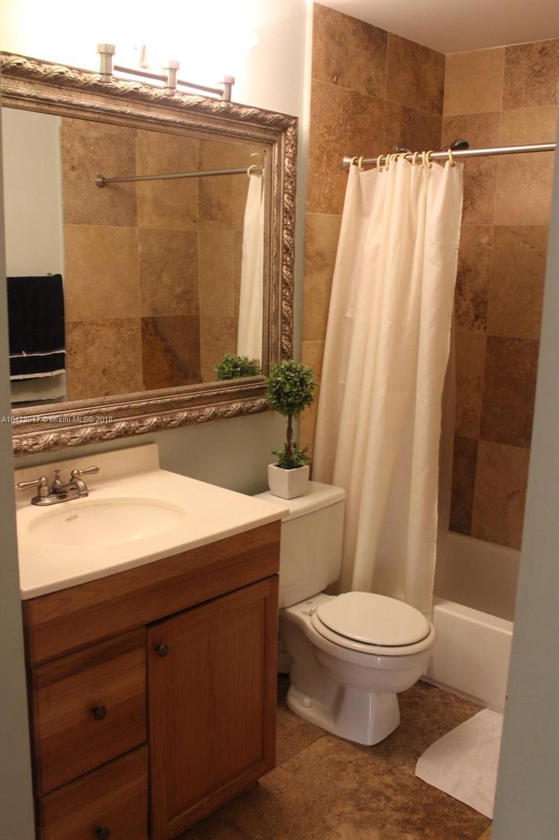 9511 Southwest 138th Place, Unit 9511 Miami, FL 33186 - Photo 15 of 17 a bathroom with a sink a toilet a mirror and shower