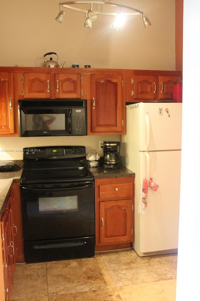 9511 Southwest 138th Place, Unit 9511 Miami, FL 33186 - Photo 8 of 17 a kitchen with stainless steel appliances granite countertop a stove a refrigerator and a microwave oven