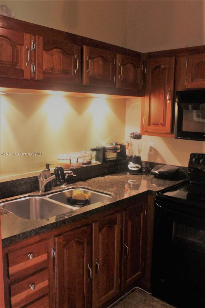 9511 Southwest 138th Place, Unit 9511 Miami, FL 33186 - Photo 9 of 17 a kitchen with granite countertop a sink and a stove
