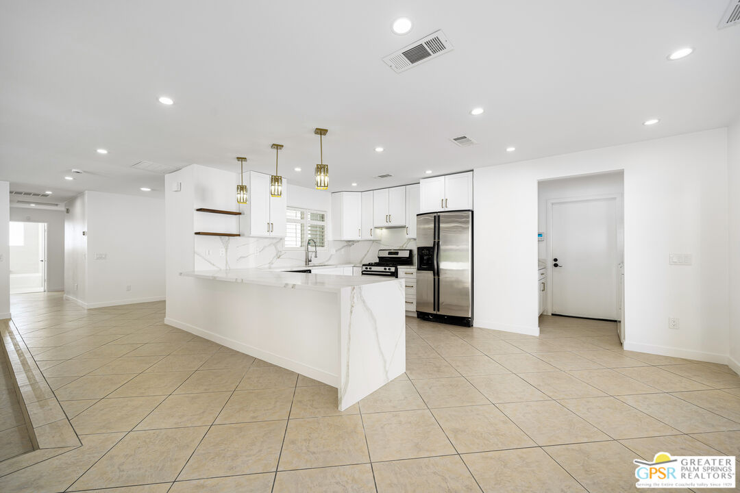 2750 East Vincentia Road Palm Springs, CA 92262 - Photo 24 of 55 a large white kitchen with kitchen island white cabinets and stainless steel appliances