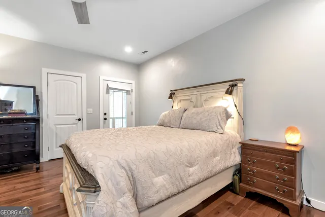 a spacious bedroom with a bed and a dresser with mirror