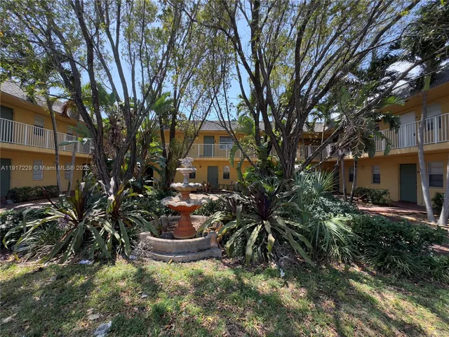 a view of a backyard with potted plants and large trees