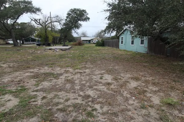 a backyard of a house with large trees and wooden fence