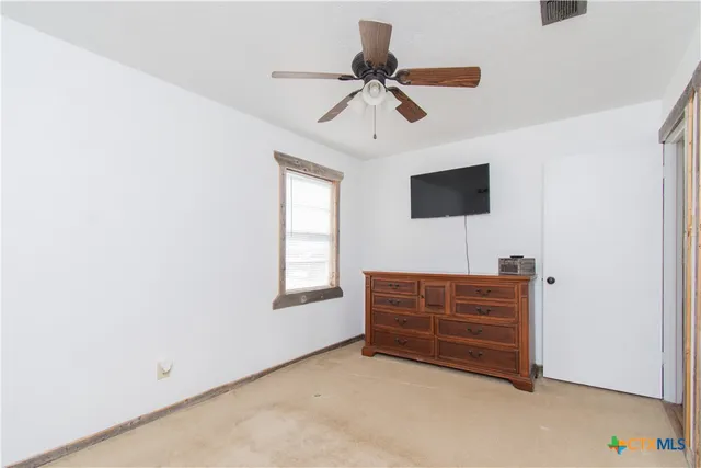 an empty room with a window and a fan