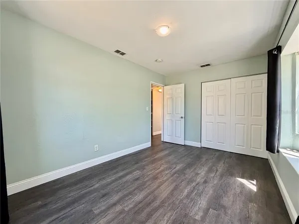 a view of an empty room with wooden floor and a window