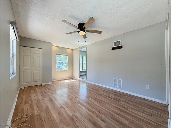 a view of an empty room with window and wooden floor