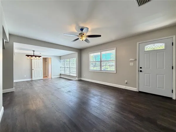 a view of an empty room with wooden floor and a window