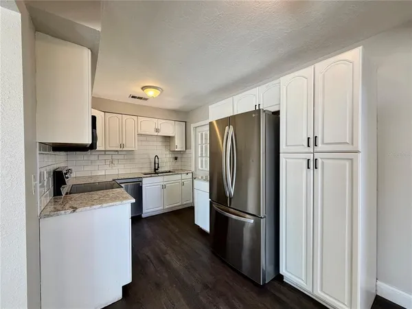 a kitchen with a refrigerator stainless steel appliances wooden floor and cabinets