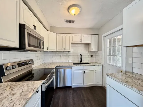 a kitchen with stainless steel appliances granite countertop a sink stove and microwave