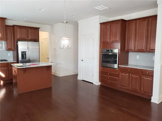 a kitchen with stainless steel appliances granite countertop a refrigerator a sink dishwasher and a stove with wooden floor