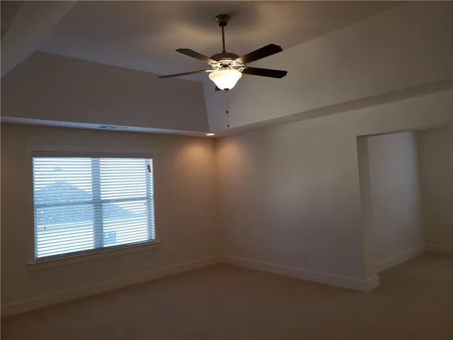 an empty room that has a window and a fan