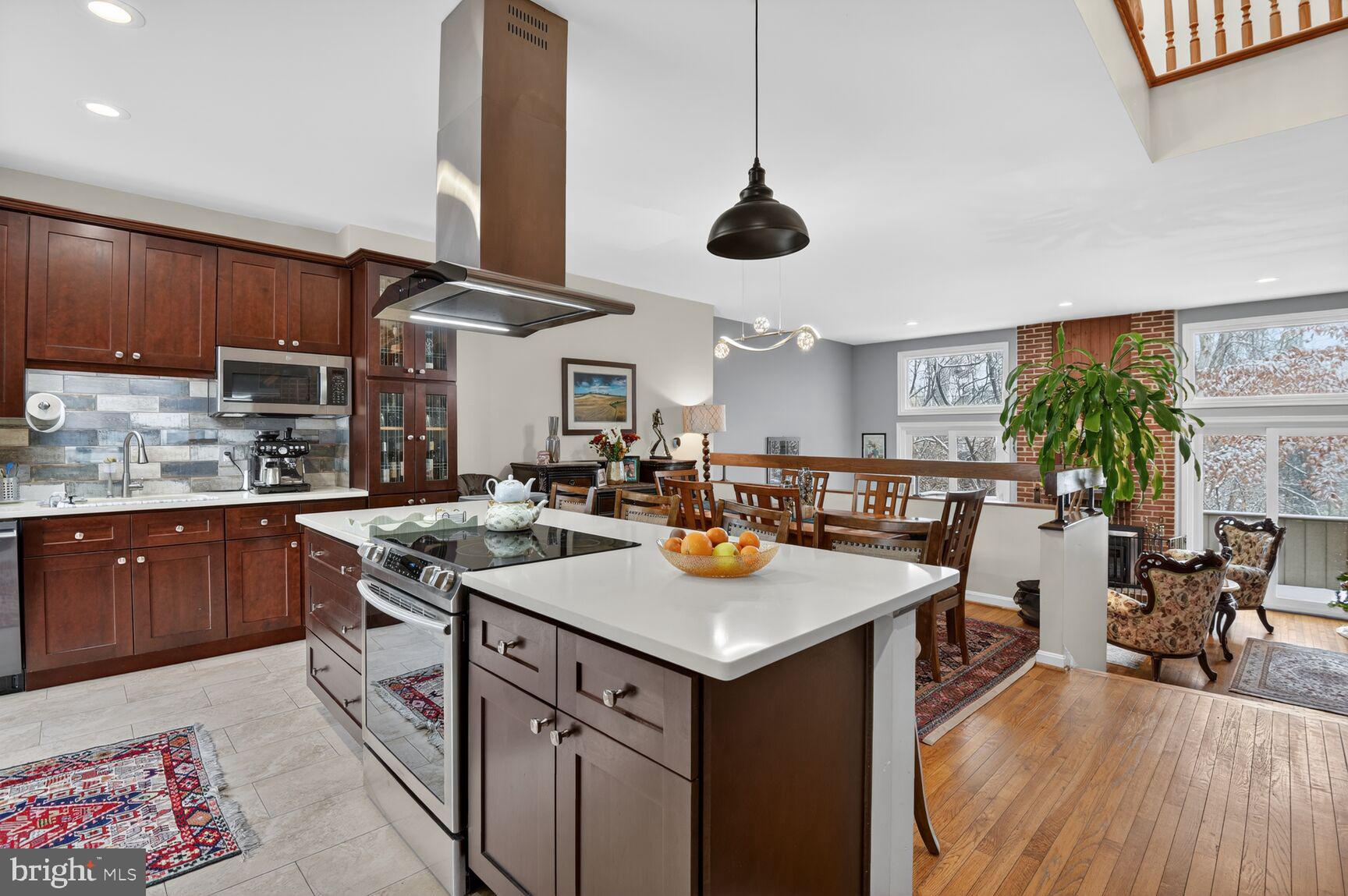 a kitchen with a stove a counter space a sink and living room view