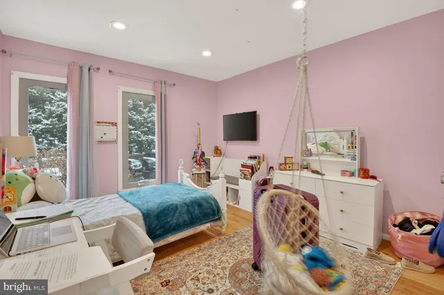 a bedroom with furniture a flat screen tv and a window