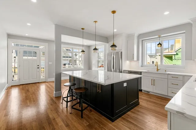 a kitchen with stainless steel appliances granite countertop a sink a stove a refrigerator and wooden floor