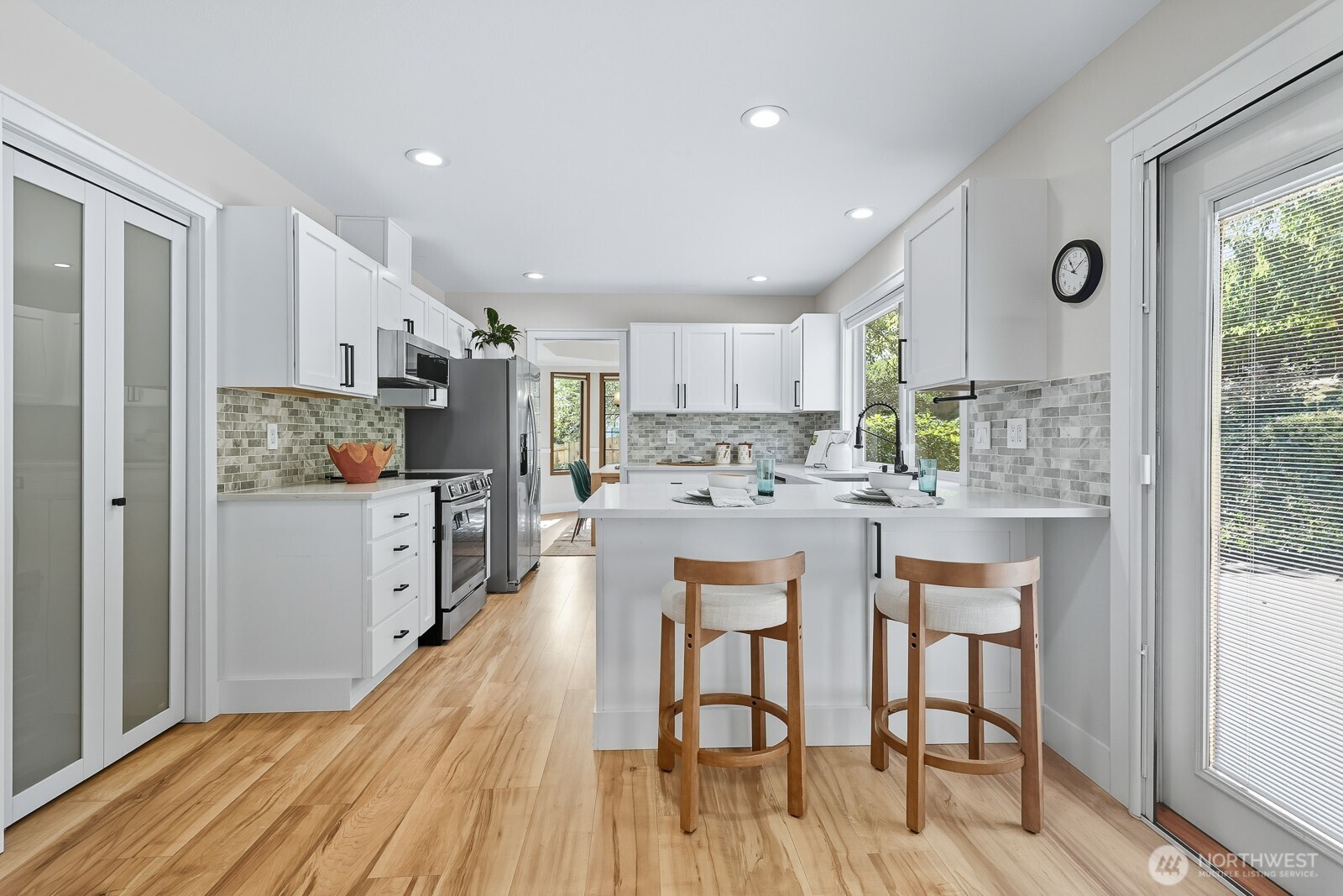 2750 214th Street Southwest Brier, WA 98036 - Photo 15 of 39 a kitchen with stainless steel appliances kitchen island granite countertop a refrigerator a stove a sink dishwasher and white cabinets with wooden floor