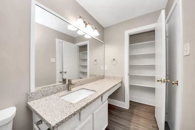 a bathroom with a granite countertop sink a toilet and a mirror