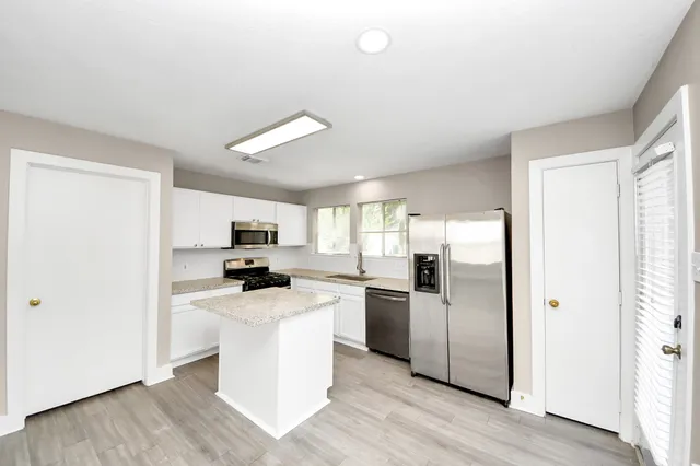 a kitchen with a refrigerator a stove cabinets and wooden floor