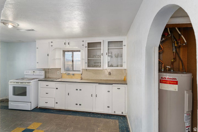482 West 100 N Street Beaver, UT 84713 - Photo 10 of 41 Kitchen featuring white electric range, electric water heater, white cabinetry, glass insert cabinets, and backsplash