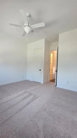 an empty room with windows and ceiling fan